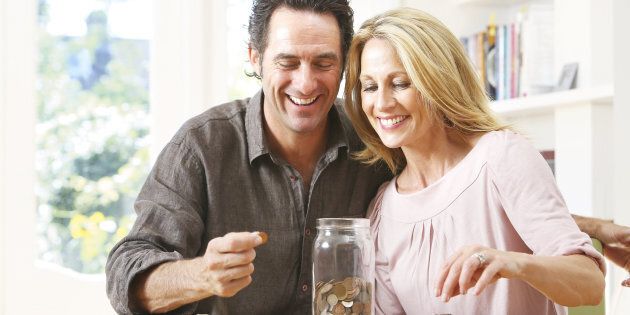 Middle aged couple counting coins into jar
