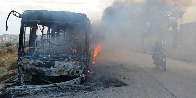 A man on a motorcycle drives past burning buses while en route to evacuate ill and injured people from the besieged Syrian villages of al-Foua and Kefraya, after they were attacked and burned, in Idlib province, Syria December 18, 2016. REUTERS/Ammar Abdullah