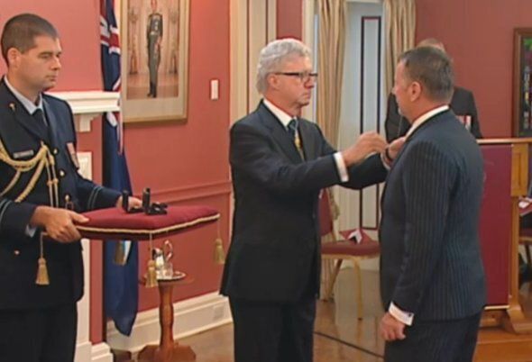Queensland Governor Paul de Jersey presents a bravery award to John Tyson, who received it on behalf of his late son Jordan Rice.
