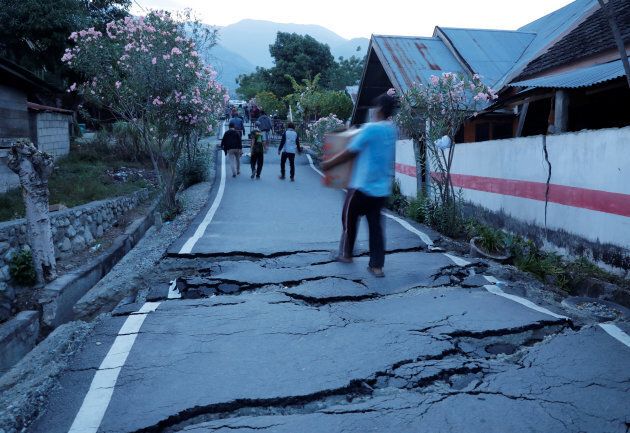 Residents walk on cracked tarmac as they carry their belongings after an earthquake hit at Balaroa sub-district in Palu, Sulawesi Island, Indonesia October 1, 2018.