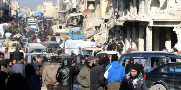 Rebel fighters and civilians wait near damaged buildings to be evacuated from a rebel-held sector of eastern Aleppo, Syria December 18, 2016. Picture taken December 18, 2016. REUTERS/Abdalrhman Ismail