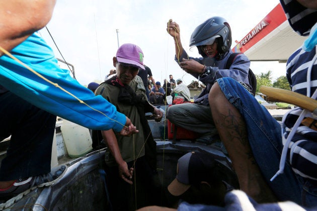 People collect gasoline from the ruins of a gas station after the earthquake that hit Palu, in Indonesia's Sulawesi island, October 3, 2018.