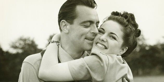 Young couple embracing in field, man kissing woman, (B&W)