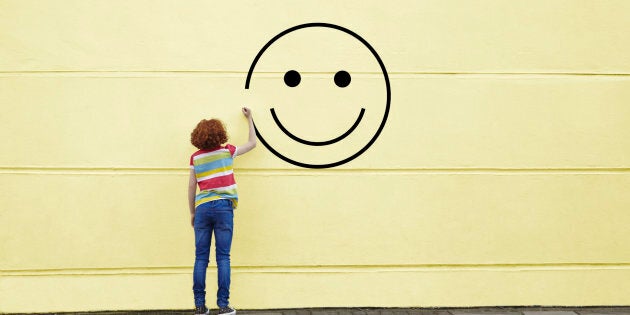 Girl drawing smiley face on to a wall