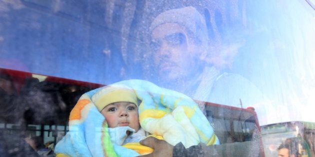 A man with a baby rides a bus to be evacuated from a rebel-held sector of eastern Aleppo, Syria December 18, 2016. Picture taken December 18, 2016. REUTERS/Abdalrhman Ismail