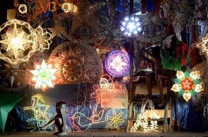 A boy crouches beside Christmas lanterns in the Philippines.