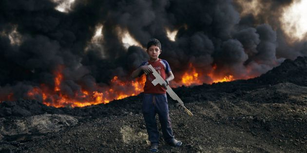 Zaer Ibrahim*, 8 plays by the burning oil fields in Qayyarah. *Name changed to protect identity
