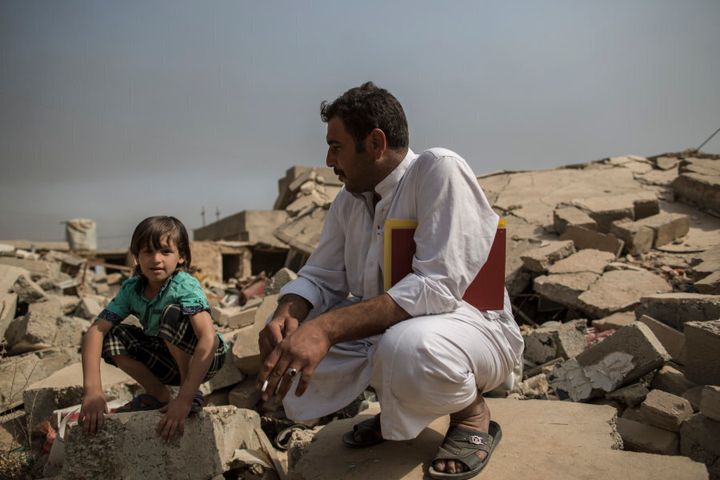 Mokhtar (village head) Nisr Amr, 35, sits with his son in the ruins of his father's house in the village of Imam Gharbi, some 70km south of Mosul, Iraq, on October 13, 2016. The house was destroyed by Islamic State, when they took control of the village in 2014. Fighters came to arrest his father, who was a police officer. He resisted, killing four of them, but was eventually killed. His house was destroyed in retribution. The army re-took the village in August.