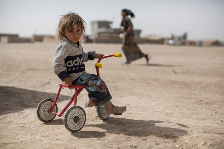 *Jasm, 2, plays on a trike in a camp for displaced people in the village of Tinah some 70km south of Mosul, Iraq, on October 14, 2016. Jasm's family lived a few kilometres away in the village of Imam Gharbi, which had been controlled by ISIS since 2014. After the army re-took the village in August and Jasm's family fled the fighting, during which their house was destroyed by shelling.