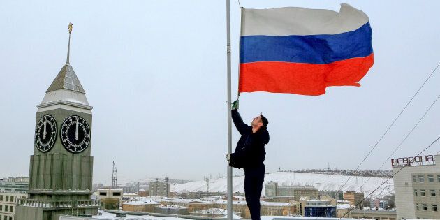 A worker lowers the Russian national flag to half-mast on a roof of the city administration building, as the country observes a day of mourning for victims of the Tu-154 plane which crashed into the Black Sea on its way to Syria on Sunday, in Krasnoyarsk, Russia, December 26, 2016. REUTERS/Ilya Naymushin TPX IMAGES OF THE DAY