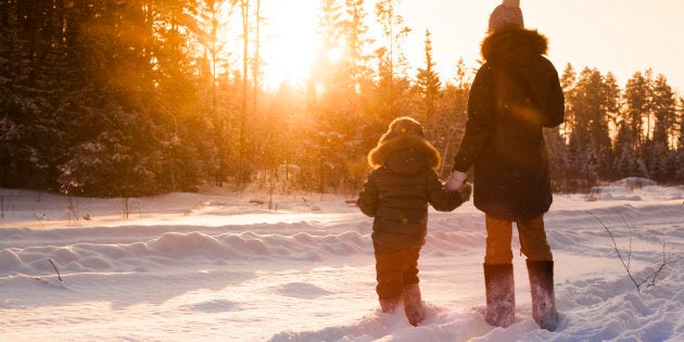 Mother and son walking in snowy forest clearing