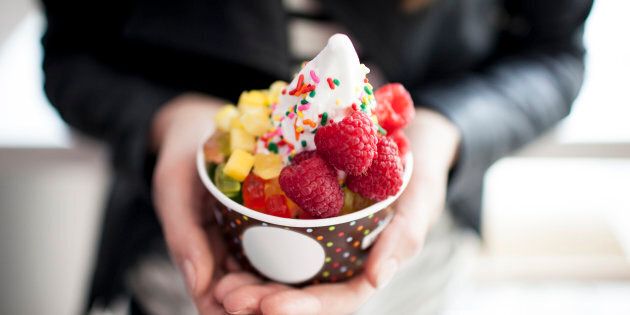 Woman holding a cup of frozen yogurt and fruit