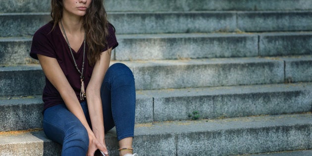 Sad girl feeling sad and sitting on stairs outside. Creative crop – no face