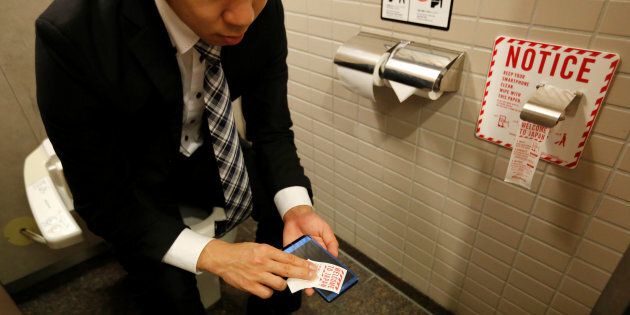 A man demonstrates a toilet roll for wiping smartphones, installed by Japanese mobile phone company NTT Docomo, in a high-tech bathroom equipped with bidet and heated seat at Narita international airport in Narita, Japan, December 28, 2016. REUTERS/Toru Hanai