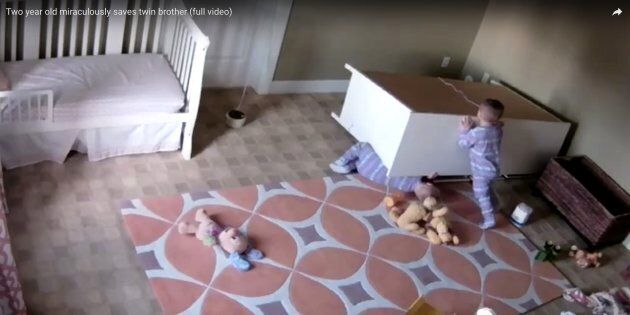 The 2-year-old boy is seen pushing a dresser off of his twin brother after it toppled on him in their bedroom last week.