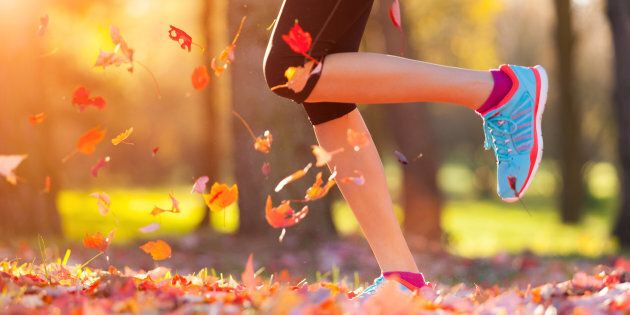 Close up of feet of woman runner running in autumn leaves, concept of training exercise