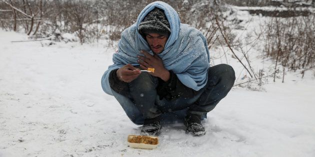 A migrant eats free food during a snowfall outside a derelict customs warehouse in Belgrade, Serbia January 9, 2017. REUTERS/Marko Djurica TPX IMAGES OF THE DAY