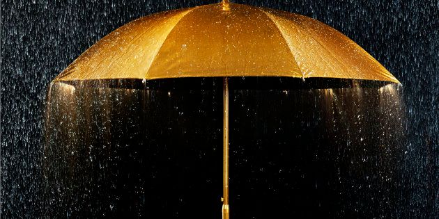 Conceptual photograph of a golden umbrella with rain.