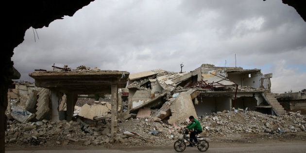 A boy rides a bicycle past damaged buildings in the rebel held besieged city of Douma, in the eastern Damascus suburb of Ghouta, Syria January 8, 2017. REUTERS/Bassam Khabieh