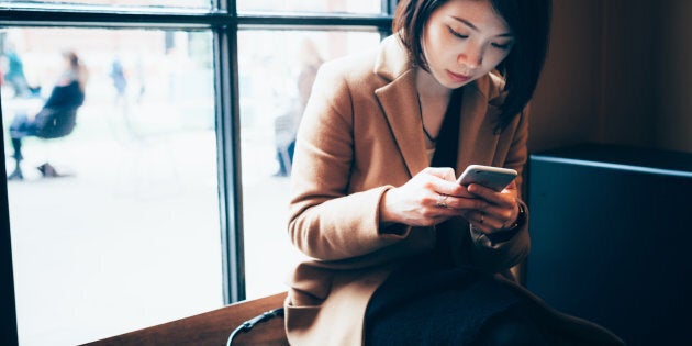 Businesswoman using cell phone in library