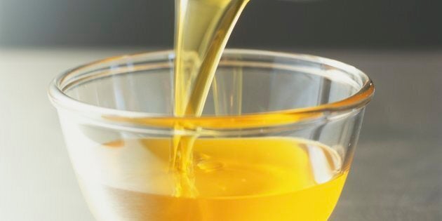 Pouring clarified butter from pan into glass bowl.