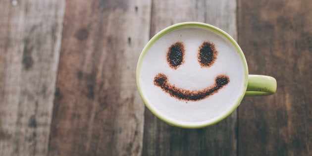 Happy face on coffee cup on wooden background with vintage colour effect. Still life.