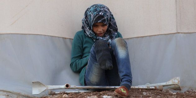 An internally displaced Syrian girl with an amputated leg checks her phone at the Bab Al-Salam refugee camp, near the Syrian-Turkish border, northern Aleppo province, Syria January 19, 2017. REUTERS/Khalil Ashawi