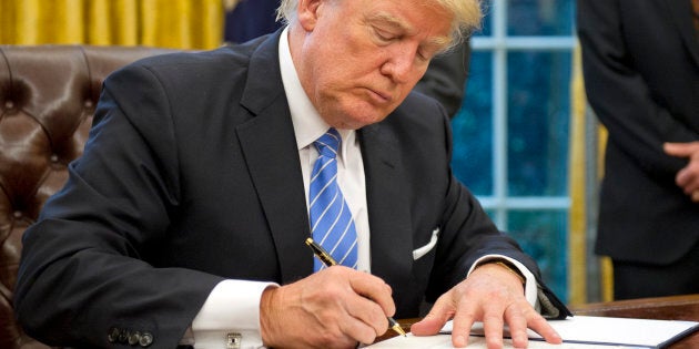 WASHINGTON, DC - JANUARY 23: (AFP OUT) U.S. President Donald Trump signs the last of three Executive Orders in the Oval Office of the White House in Washington, DC on Monday, January 23, 2017. These concerned the withdrawal of the United States from the Trans-Pacific Partnership (TPP), a US Government hiring freeze for all departments but the military, and 'Mexico City' which bans federal funding of abortions overseas. (Photo by Ron Sachs - Pool/Getty Images)