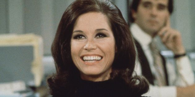 American actress and commediene Mary Tyler Moore (as Mary Richards) smiles broadly as she sits at a desk in a scene from 'The Mary Tyler Moore Show' (also known as 'Mary Tyler Moore'), Los Angeles, California, 1970. (Photo by CBS Photo Archive/Getty Images)