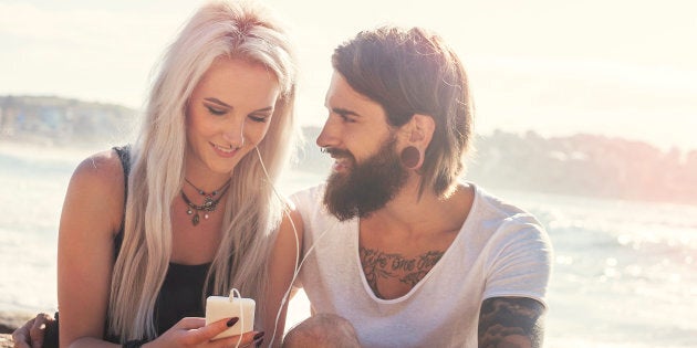 Young rebellious couple listening together to music at the beach. Bondi Beach, NSW Australia