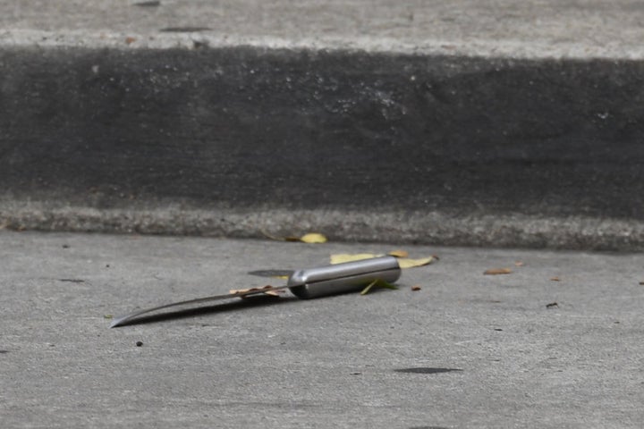 Another knife can be seen on the ground where police have established a crime scene.