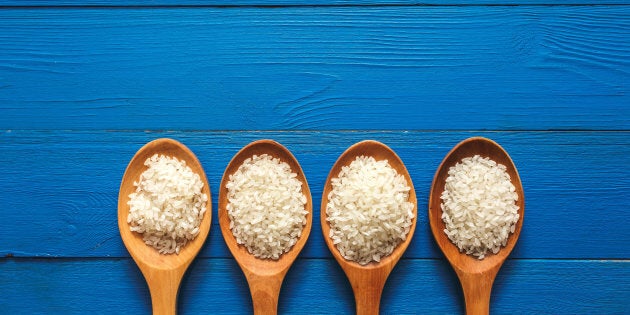 Rice on wooden spoon with blue color wood.