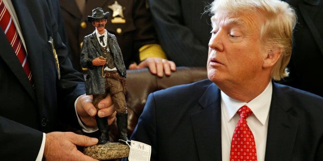 U.S. President Donald Trump receives a figurine of a sheriff during a meeting with county sheriffs at the White House in Washington, U.S. February 7, 2017. REUTERS/Kevin Lamarque TPX IMAGES OF THE DAY
