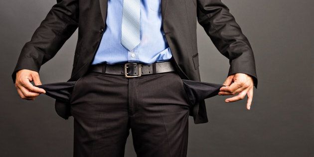Business man showing his empty pockets on gray background