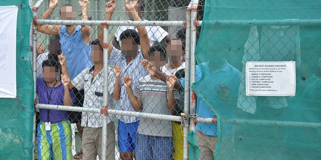 Asylum-seekers look through a fence at the Manus Island detention centre in Papua New Guinea March 21, 2014.