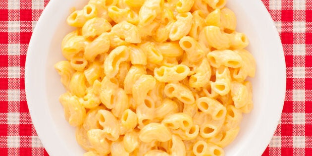 Top view of white dish full of macaroni and cheese over checked tablecloth