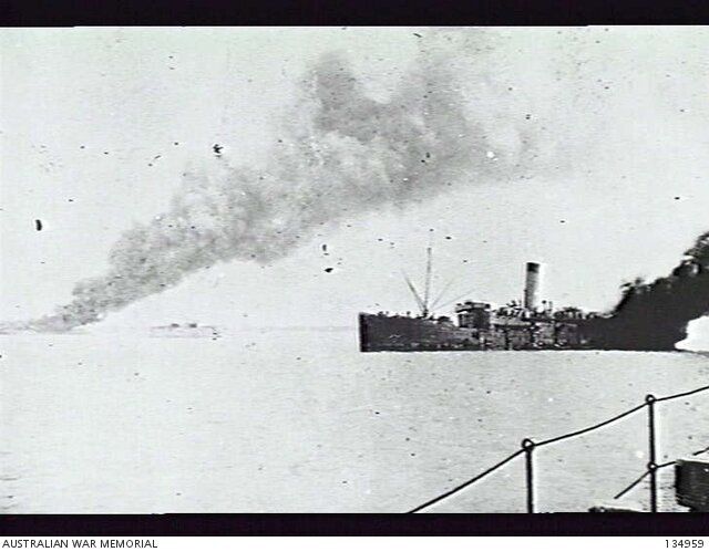 The SS Zealandia, an ammunition ship, on fire in the harbour after bing bombed during the air raid. on the left, smoke rises from the bombed Neptuna