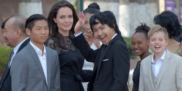 Angelina Jolie and her children gesture to media in front of the royal residence for a meeting with Cambodian King Norodom Sihamoni in Siem Reap on Feb. 18.