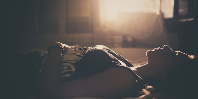 Sad girl in bed, backlit scene. Desaturated image.