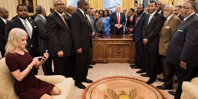 Counselor to the President Kellyanne Conway (L) checks her phone after taking a photo as US President Donald Trump and leaders of historically black universities and colleges pose for a group photo in the Oval Office of the White House before a meeting with US Vice President Mike Pence February 27, 2017 in Washington, DC. / AFP / Brendan Smialowski (Photo credit should read BRENDAN SMIALOWSKI/AFP/Getty Images)