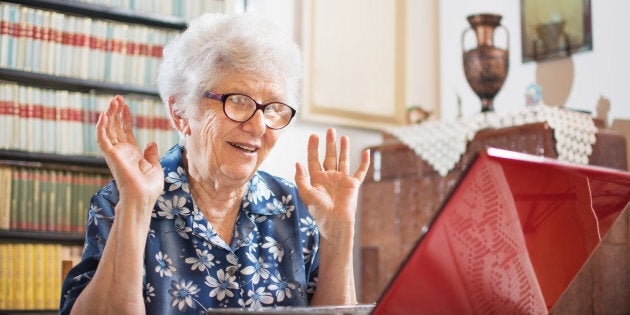 Surprised senior woman sitting in front of laptop at home.