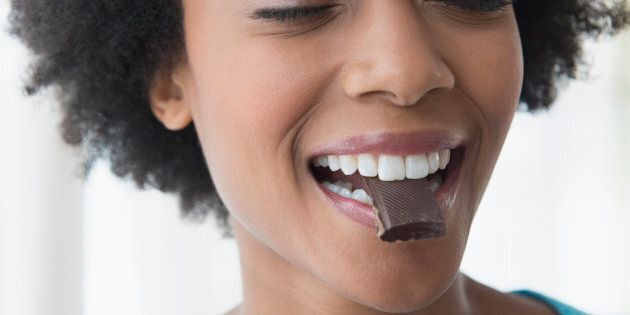 Close up of African American woman eating square of chocolate