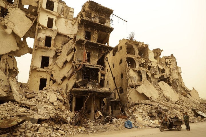 A Syrian man drives his vehicle past destruction in the once rebel-held Aghiour neighbourhood in Aleppo during a sandstorm on March 10, 2017.