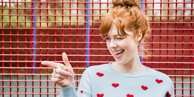 Young woman winking and pointing.