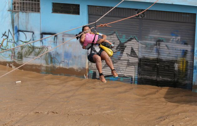 A woman and a child are evacuated by zip line after the Huaycoloro river flooded, sending torrents of mud and water rushing through the streets of Lima.