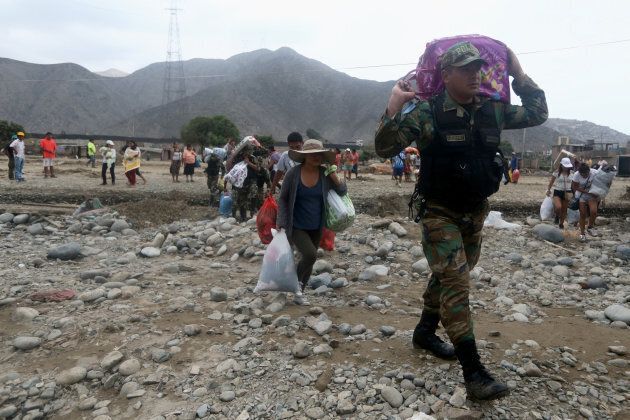 Police officers and residents salvage their belongings and head to safety after a massive landslide destroyed homes in the Huachipa district of Lima.