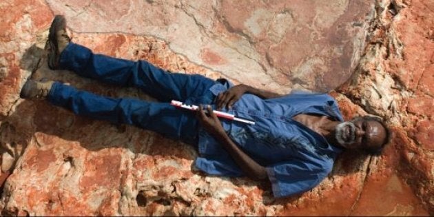 A man next to the dinosaur footprint, holding a 40cm scale.