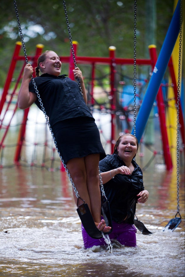 Crystal Warner (L) and Sharnia Johns (R) play on playground equipment as floodwaters caused by Cyclone...