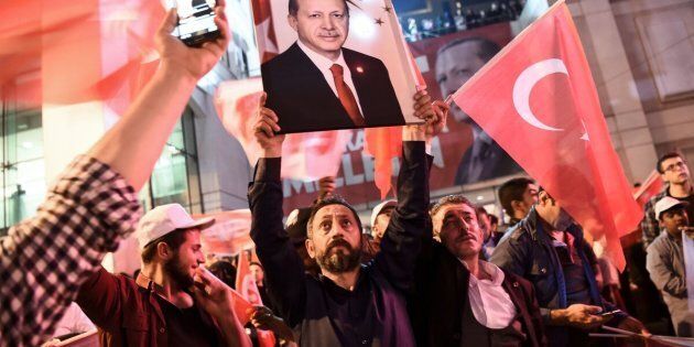 A supporter of the 'yes' brandishes a picture of Turkish president Recep Tayyip Erdogan among other supporters waving Turkish national flags during a rally on Sunday