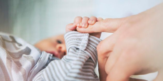 Stock image of a mother holding her baby's hand.